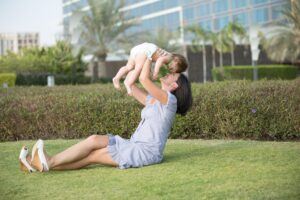 mother holding up happy baby in grass