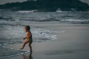 naked baby playing in ocean