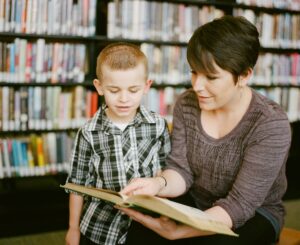 woman reading to boy in library