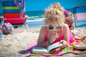 girl reading book on beach